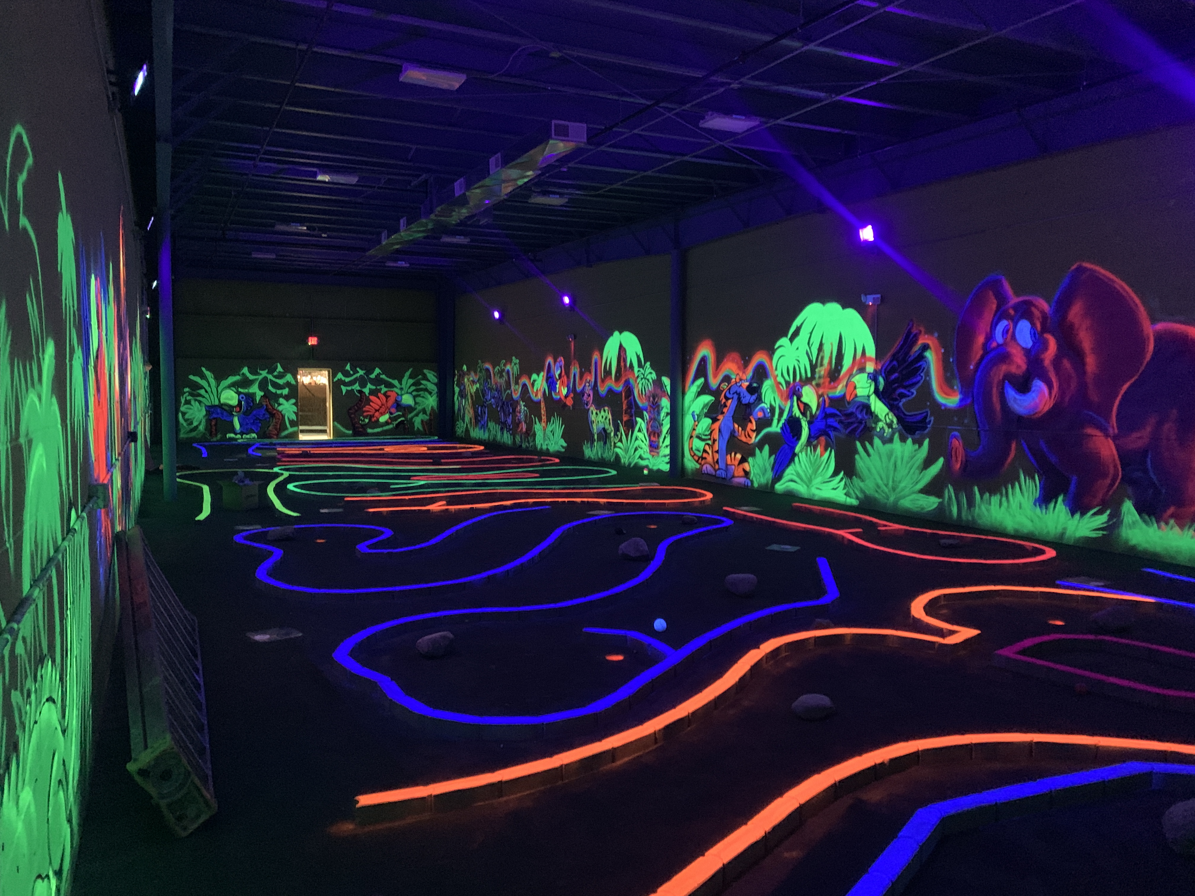 Neon glowing blacklight tropical jungle mural with elephant and palms in entertainment venue