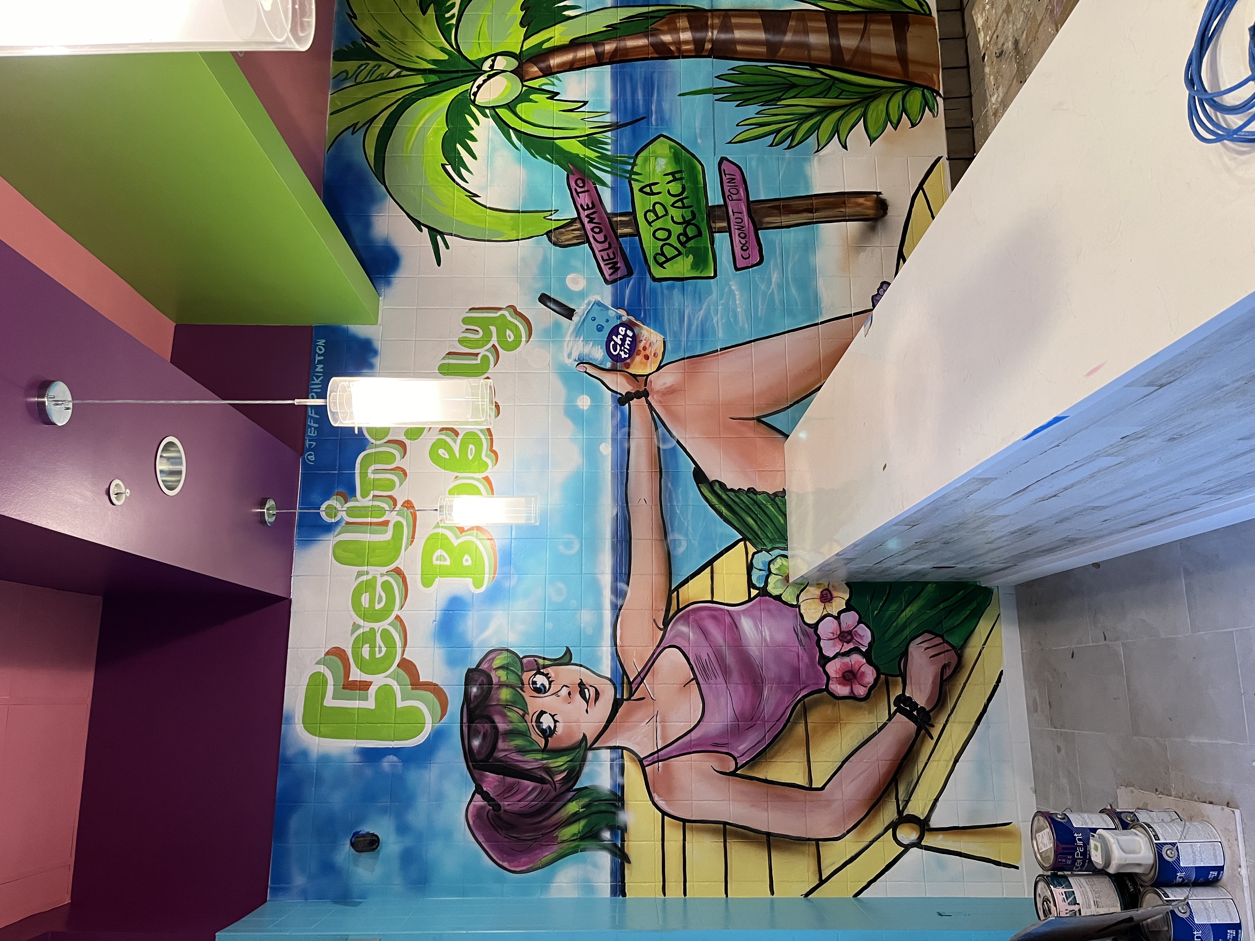 Playful cartoon tropical beach mural with relaxed woman, palms, Poba Beach signs and bubbly cocktail on tiled wall