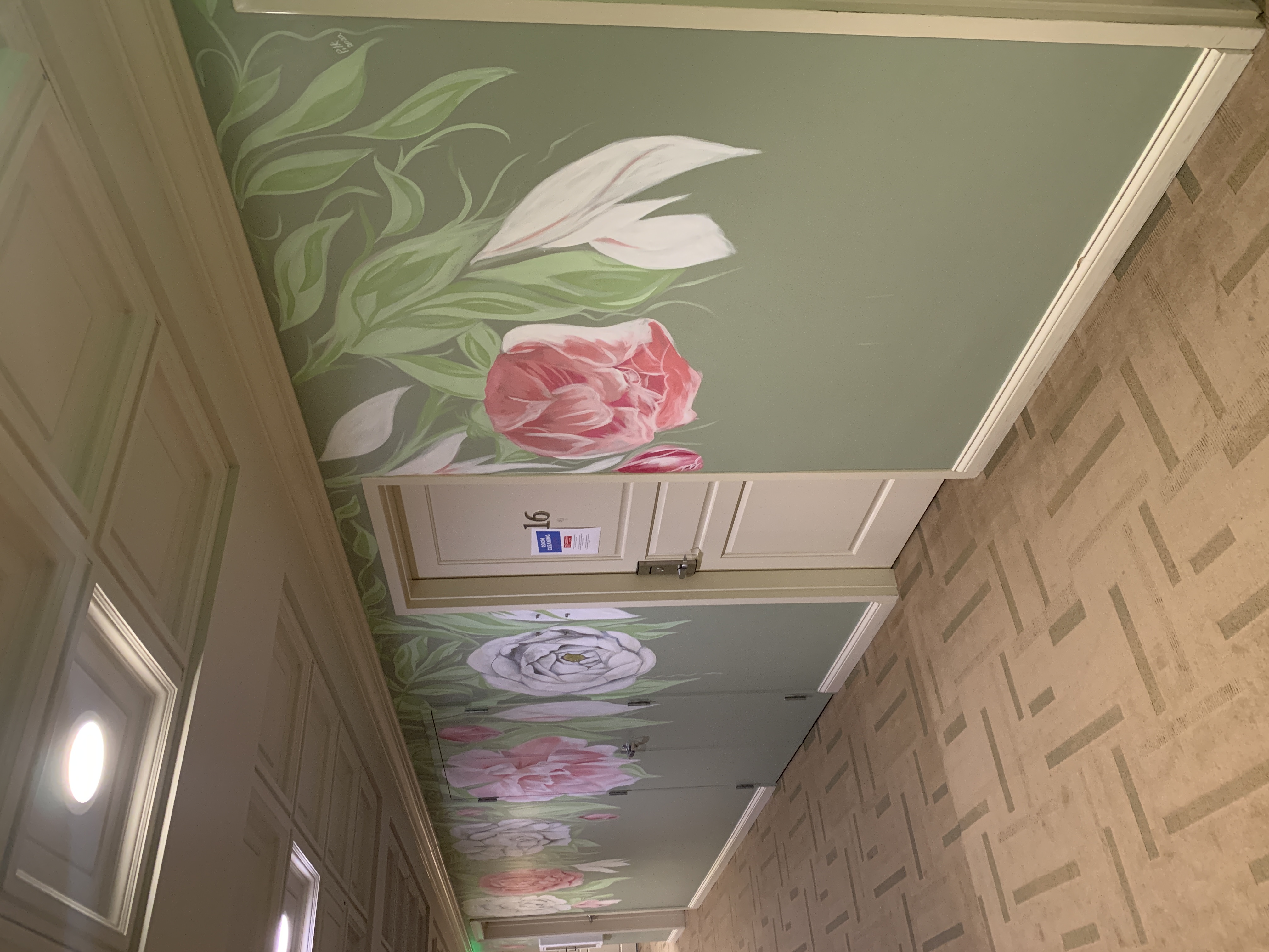 Delicate elegant pink peonies, white tulips and green leaves botanical mural on sage interior walls