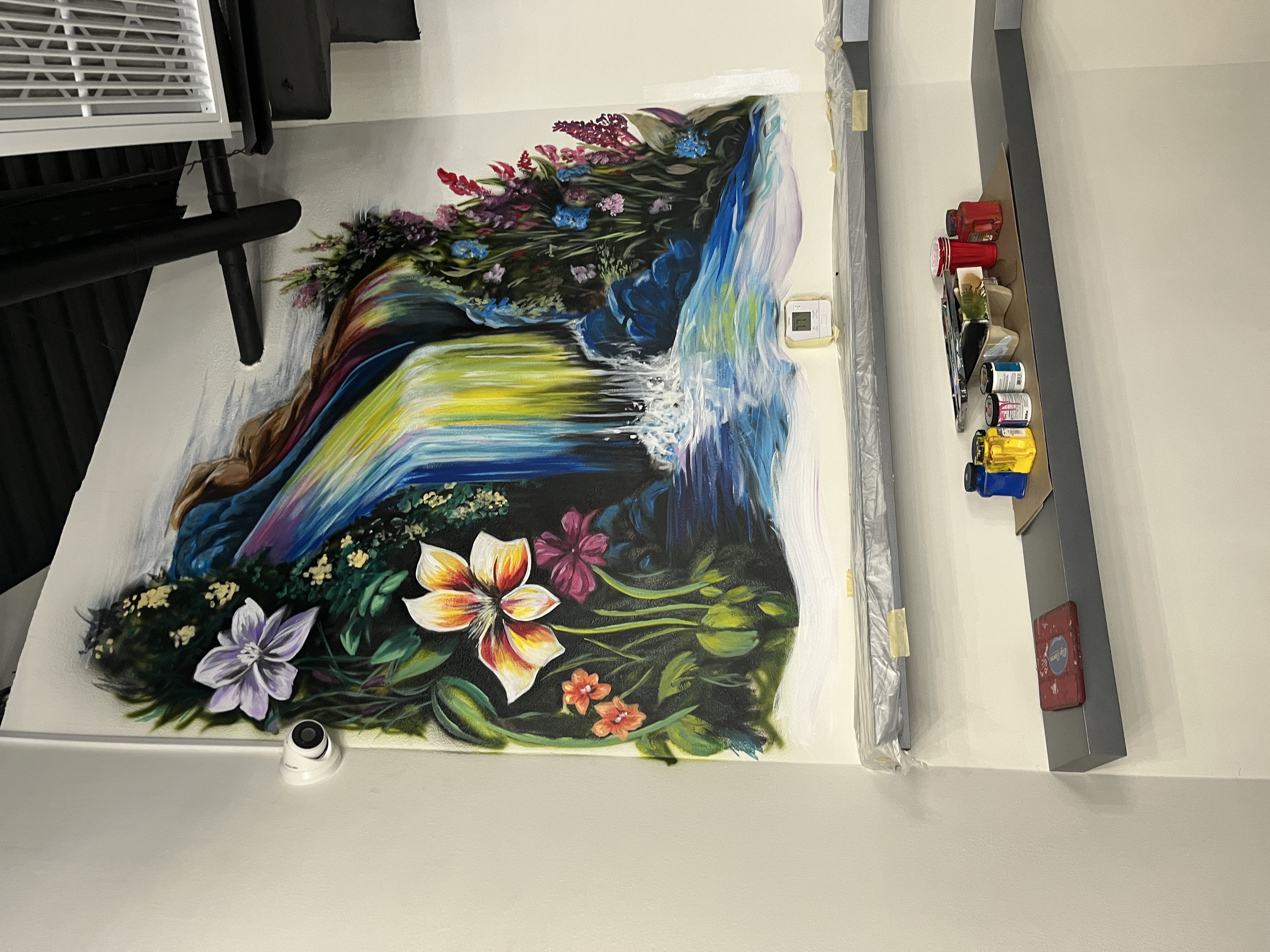 Colorful rainbow waterfall with lush tropical flowers and foliage mural in commercial interior